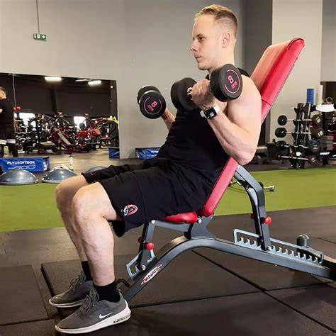 Muž cvičiaci na posilňovacej lavici s jednoručkami